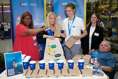 A photo of 4 employers behind a table at their stall. THe ESB staff have a lot of merchandise and are smiling for the photo. 